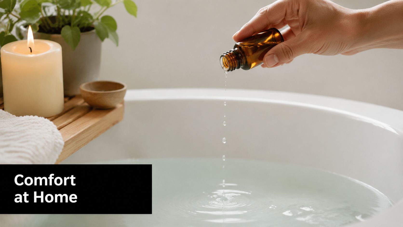 A hand pours essential oil into a relaxing bathtub filled with water next to a burning candle.