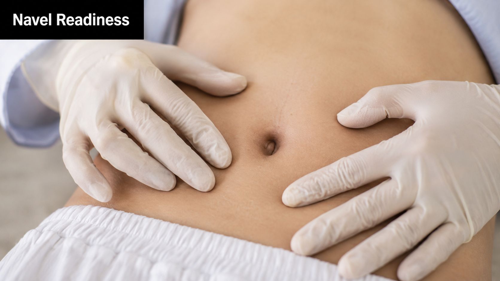 A healthcare professional wearing latex gloves gently touches the patient's belly button area for a medical assessment.